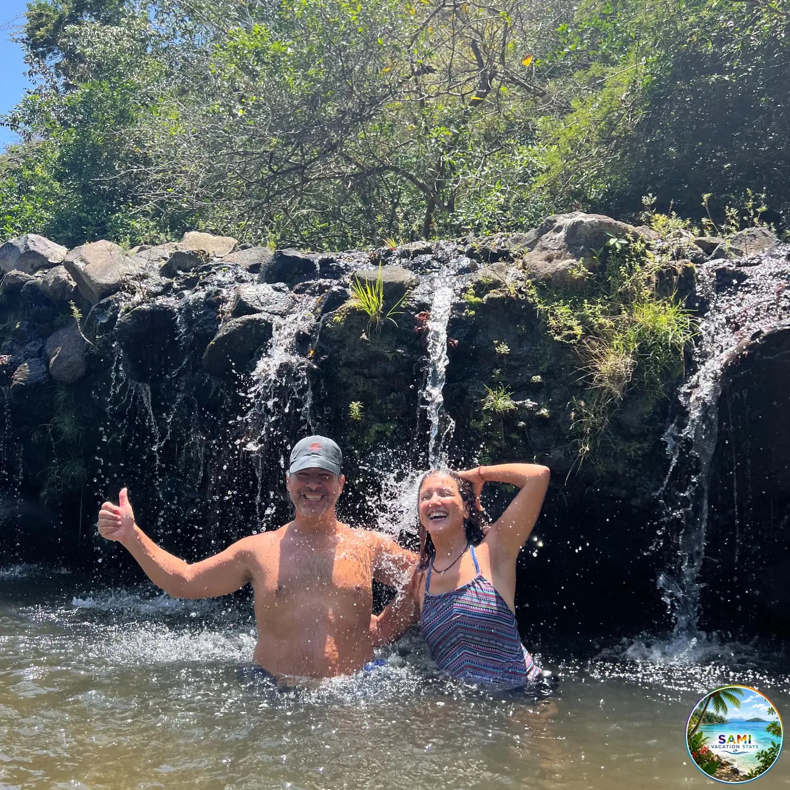 Couple splashing in a waterfall pool